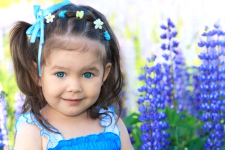 smiling little girl with big blue eyes in flowersの写真素材