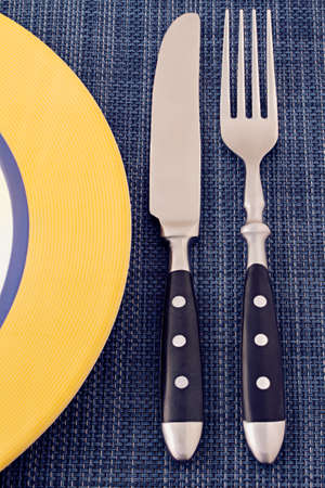 yellow plate and serving knife and fork photographed on a blue texture tableclothの写真素材