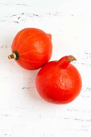 two small orange pumpkins on a white rustic boardの写真素材