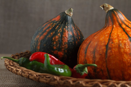 Pumpkins and hot peppers on a straw dish. Close-up.の写真素材