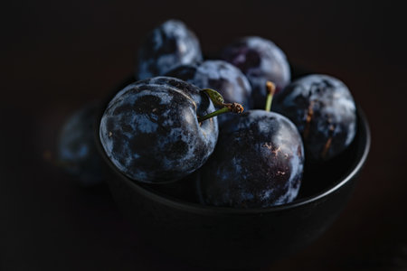 Plums in a dark bowl on a black background close-up. selective focus.の写真素材