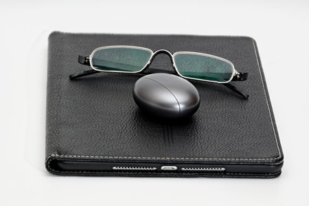 Tablet, glasses, and case with wireless headphones on white background. joke installation.の写真素材