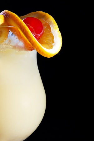 Alcohol yellow  drink in cocktail glass with piece of orange and red cherryの写真素材