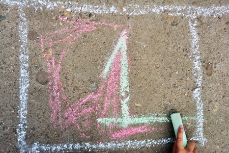 Child`s hand is writing Number 1 using colorful chalks on asphaltの写真素材
