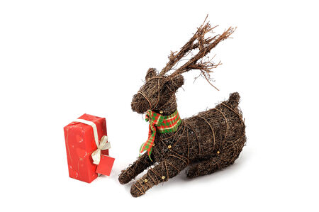 Wooden reindeer withscarf and Christmas toy next to Christmas red presentの写真素材