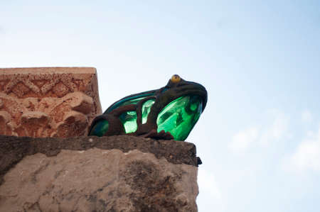 decorative glass frog on the stone against the blue skyの写真素材