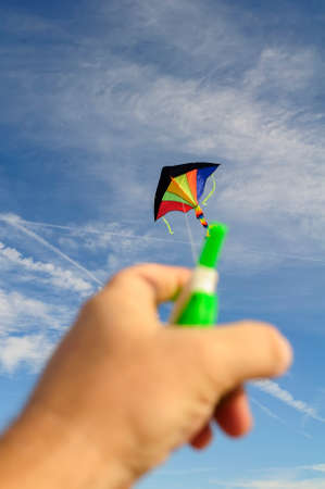 the girl starts colorful kite flying on the background of white clouds and blue skyの写真素材