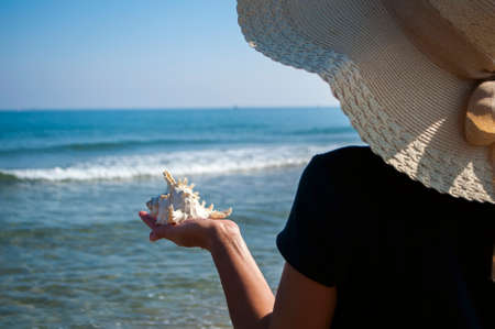 girl on the beach holding the shell against the sea