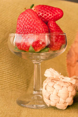 red , juicy berries in a glass vase with straw sandals