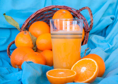 ripe orange fruits in the basket and a glass of freshly squeezed juiceの写真素材