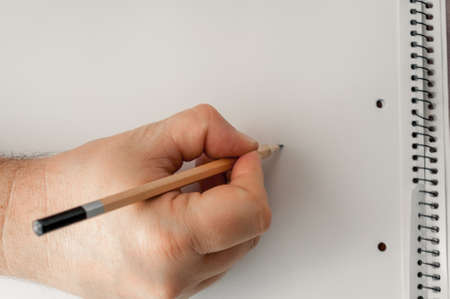 in his hand a pencil, a blank sheet of paper ready to drawの写真素材