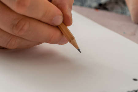 in his hand a pencil, a blank sheet of paper ready to drawの写真素材