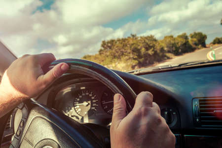 hands on the wheel machine is in forward motion. the background of sky with clouds and trees