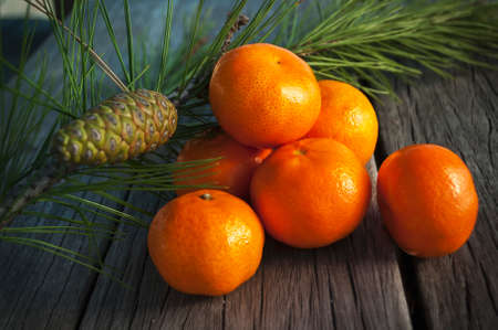 bright juicy oranges on old vintage wooden table on the background of fir branches with cones. a wonderful Christmas illustrationの写真素材