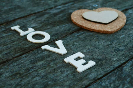the word love has white lettering on a background of old weather-beaten wood and heartの写真素材