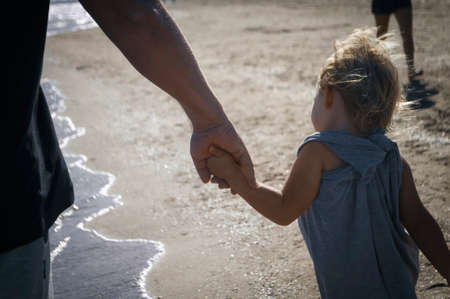 father and daughter walking on the shore holding hands