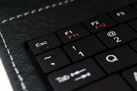 part of black keyboard laptop computer on a white background with focus on the escape buttonの写真素材