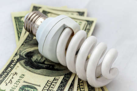 Energy saving lamp isolated on white background with moneyの写真素材