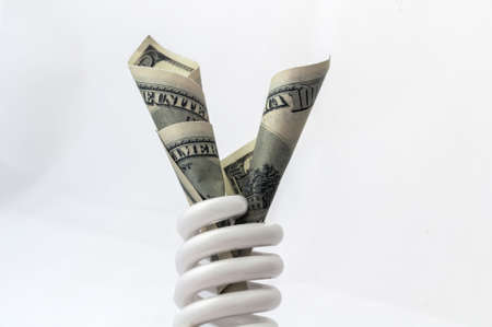 Energy saving lamp isolated on white background with moneyの写真素材