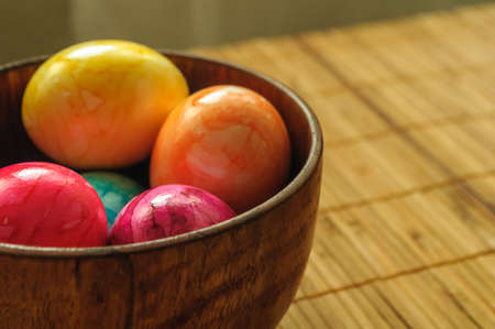 colored, painted eggs in wooden bowl on bamboo napkin. For Easterの写真素材