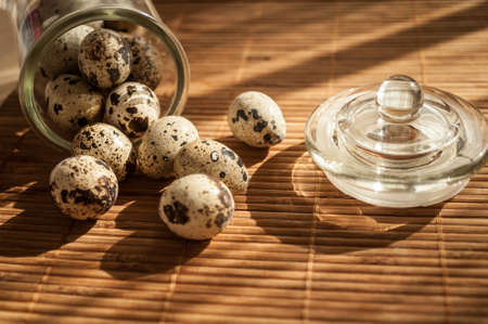 quail eggs in a decorative glass jar on the table in the sunの写真素材