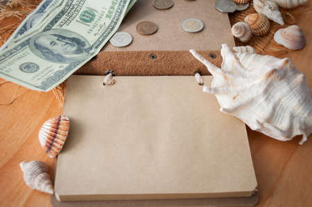 on a wooden table lies an open notebook, shells and money. planning a trip on vacationの写真素材