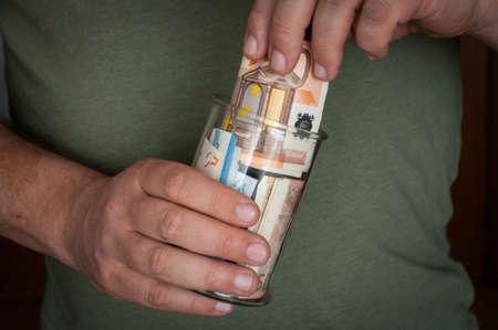 a man holds a glass jar with money. And puts or gets money