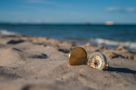 gold plated compass lying on the sand on the beachの写真素材
