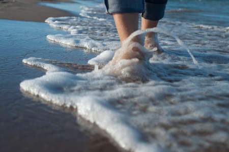 girl on the beach walking on the water,in the frame legsの写真素材