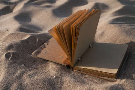open the notebook in the sand closeupの写真素材