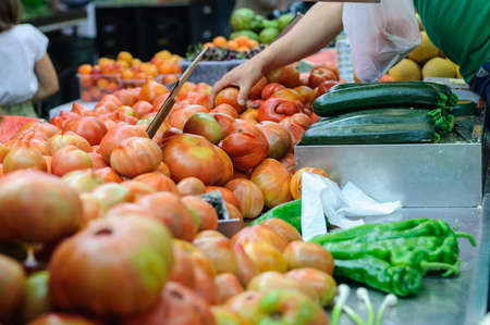 market tray with tomatoes and other vegetables, see the hands of consumersの写真素材