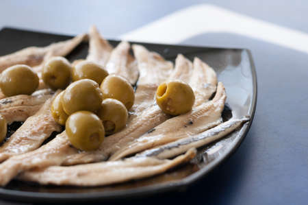 Marinated anchovies and olives on the plate, a traditional snack in Spain, diet, and healthy dish.の写真素材