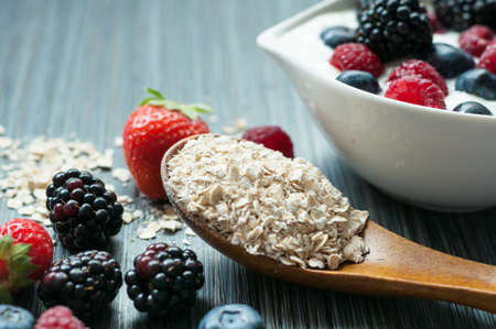 on the table, a scattering of raspberries blueberries blackberries strawberries and a spoonful of...