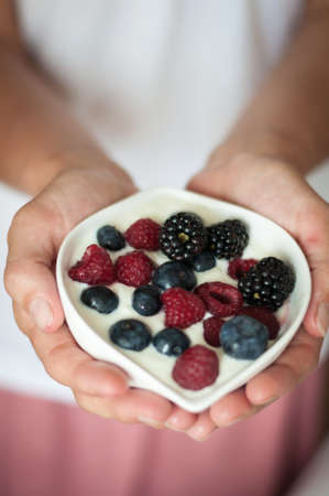 the girl offers diet vegenarian and healthy Breakfast yogurt with berriesの写真素材
