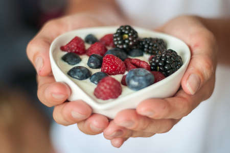 the girl offers diet vegenarian and healthy Breakfast yogurt with berriesの写真素材