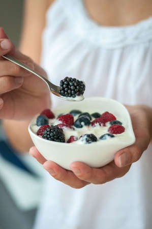 the girl offers healthy Breakfast yogurt with berriesの写真素材