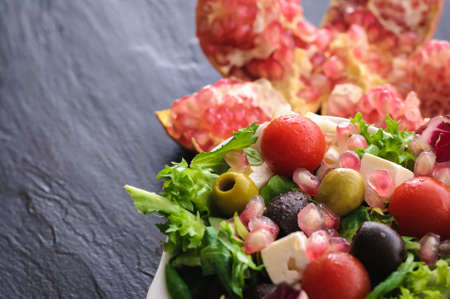 vegetarian food is salad, canonigo tomatoes olives pomegranate, and feta cheese. on a black backgroundの写真素材