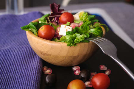 vegetarian food is salad, canonigo tomatoes olives pomegranate, and feta cheese. on a black backgroundの写真素材