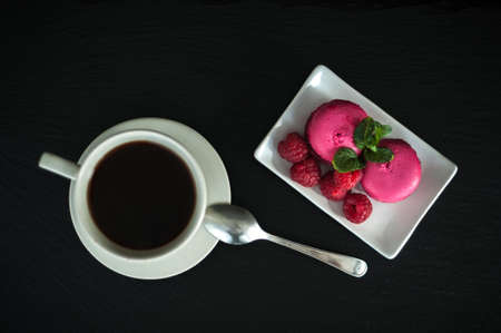 Breakfast pink macaroons raspberries with coffee on black backgroundの写真素材