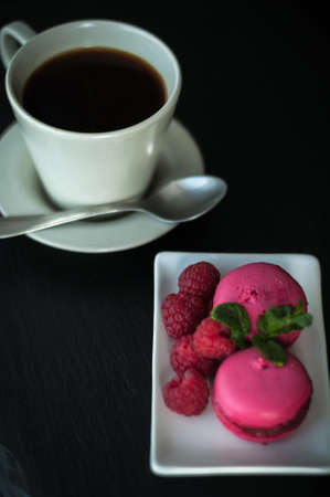 Breakfast pink macaroons raspberries with coffee on black backgroundの写真素材