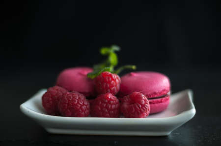 pink macaroons with raspberries on black backgroundの写真素材