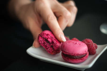 pink macaroons with raspberries on black backgroundの写真素材