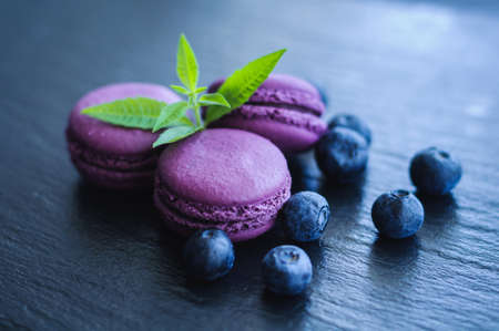 pink macaroons with blueberries on black backgroundの写真素材