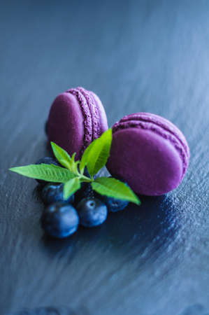 pink macaroons with blueberries on black backgroundの写真素材