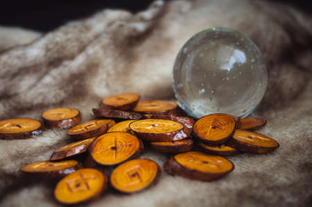 wood runes handmade fur are lying beside the crystal ball and semi-precious stones