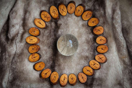 wood runes handmade fur are lying beside the crystal ball and semi-precious stonesの写真素材