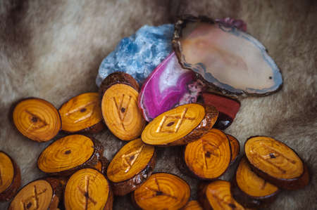 wood runes handmade fur are lying beside the crystal ball and semi-precious stonesの写真素材