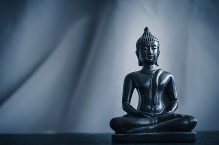 black small figurine of Buddha on a gray backgroundの写真素材