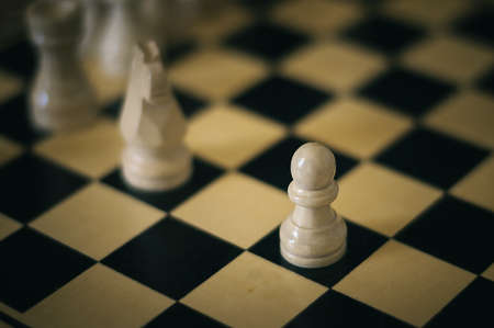 several white chess pieces on a chessboard with a pawn in the centerの写真素材
