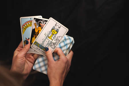 Tarot cards senior Arcana in the hands of a woman on a black backgroundの写真素材